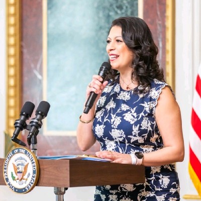Headshot of Melody Gonzales speaking in too a microphone 